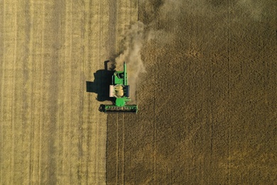 Beautiful aerial view of modern combine harvester working in field on sunny day. Agriculture industry