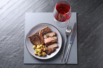 Delicious fried beef meat and vegetables served on black table, top view