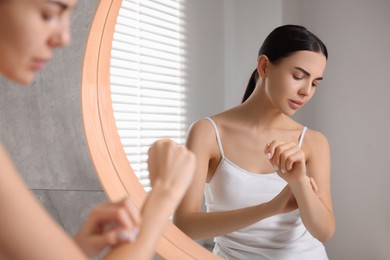 Woman with dry skin checking her arm indoors