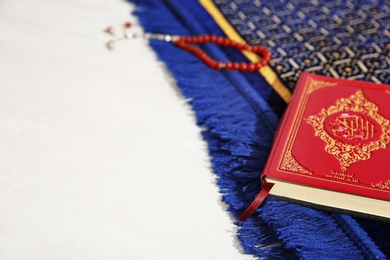 Photo of Muslim prayer beads, Quran, rug and space for text on light background