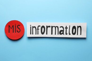 Photo of Word MISINFORMATION made with paper pieces on light blue background, flat lay