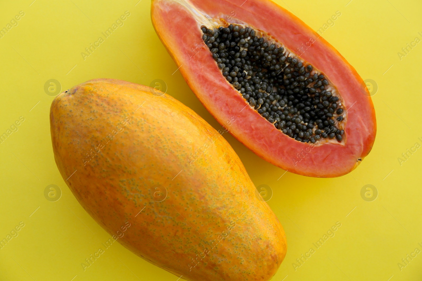 Photo of Fresh ripe cut and whole papaya fruits on light green background, flat lay