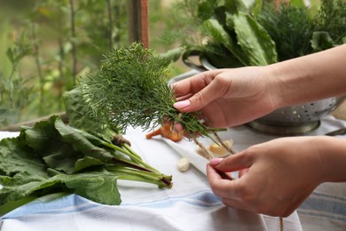 Photo of Woman with fresh green herbs and twine indoors, closeup