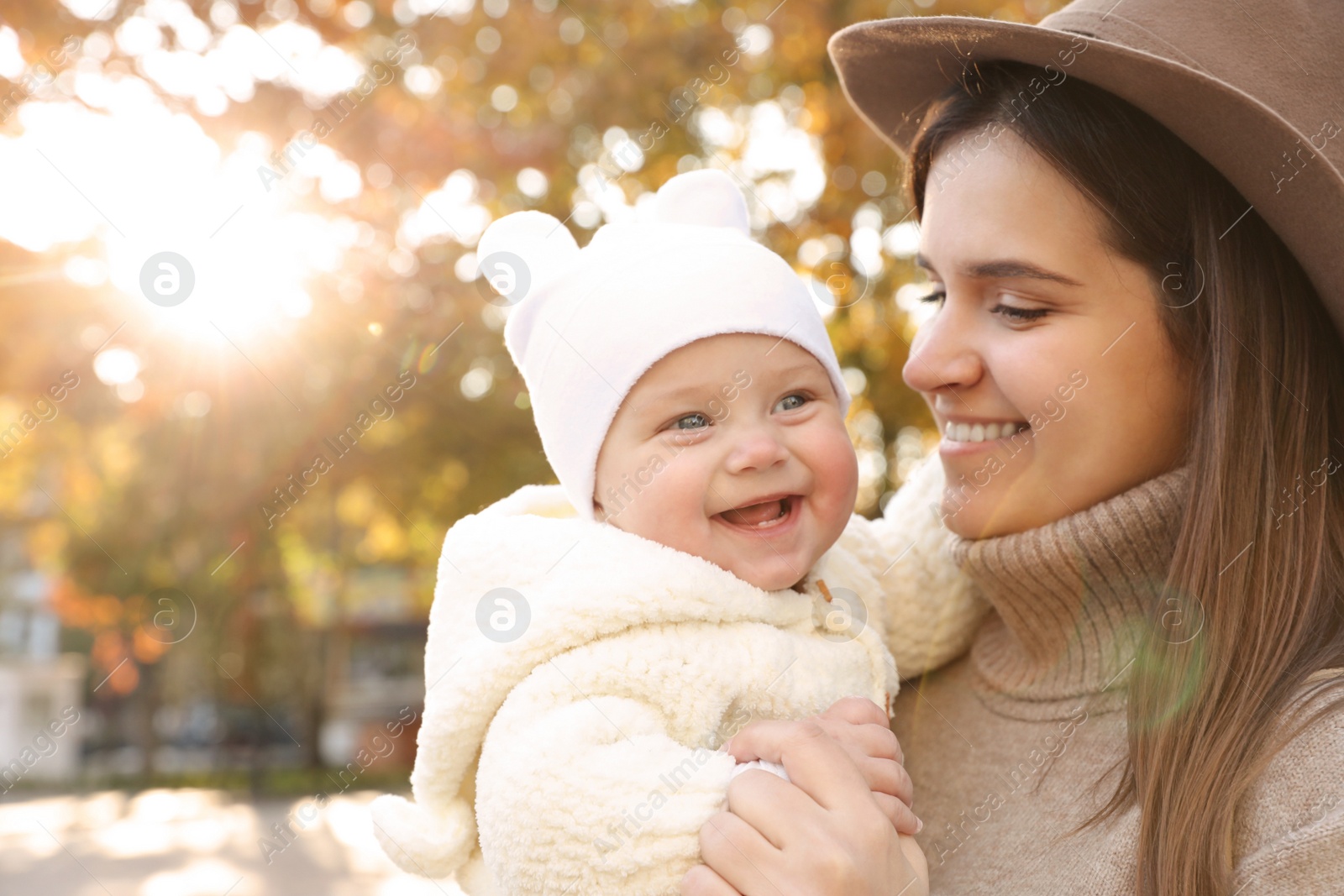 Photo of Happy mother with her baby daughter outdoors on autumn day, space for text