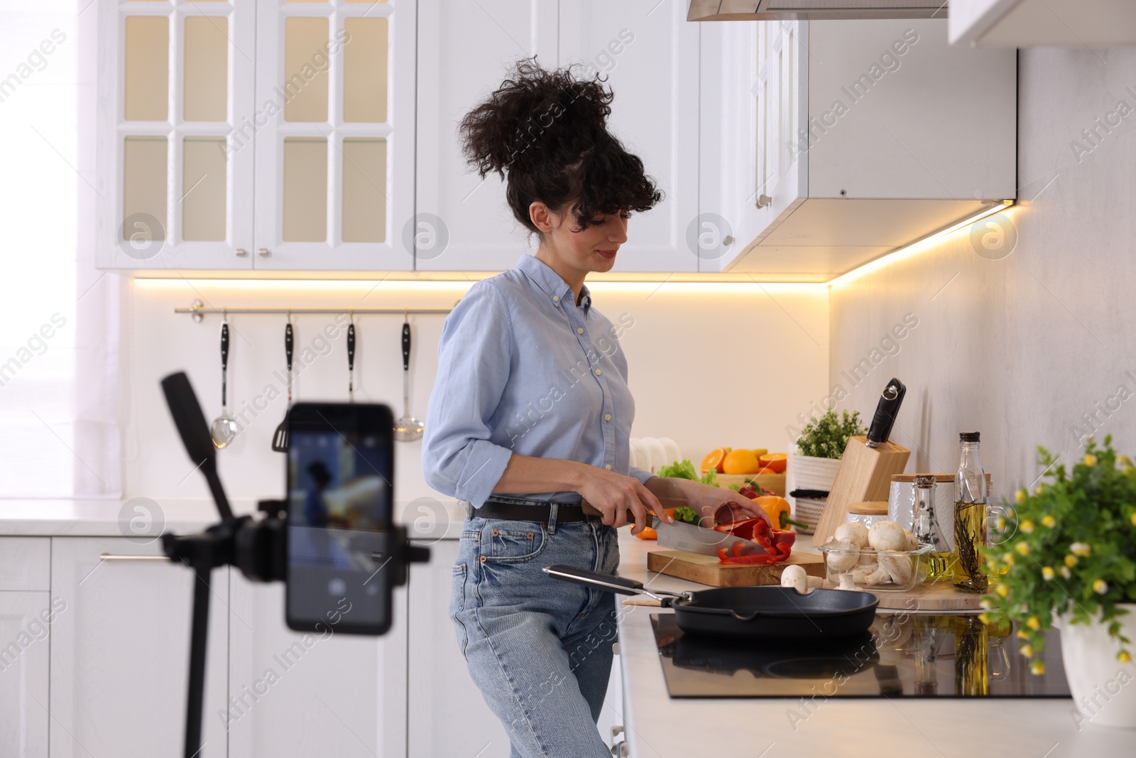 Photo of Food blogger cooking while recording video in kitchen