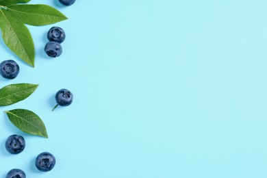 Photo of Tasty fresh blueberries with green leaves on light blue background, flat lay. Space for text