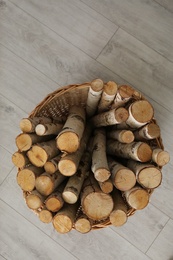 Photo of Wicker basket with firewood on floor indoors, top view