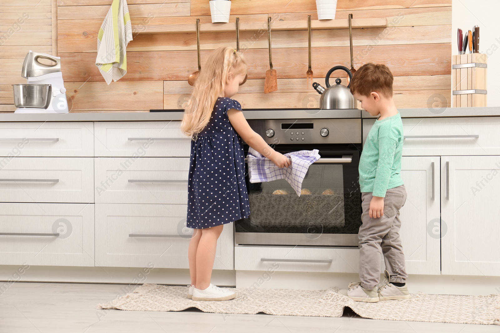 Photo of Cute children baking cookies in oven at home