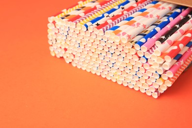 Many paper drinking straws on orange background. Space for text