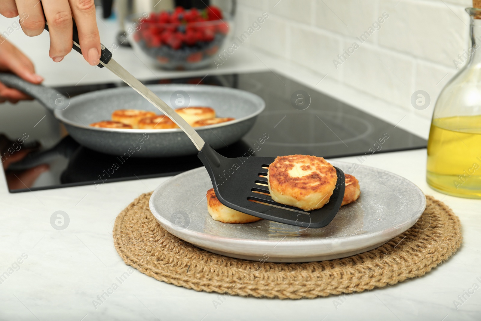 Photo of Woman frying delicious cottage cheese pancakes in kitchen, closeup