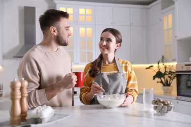 Photo of Lovely young couple cooking dough together in kitchen