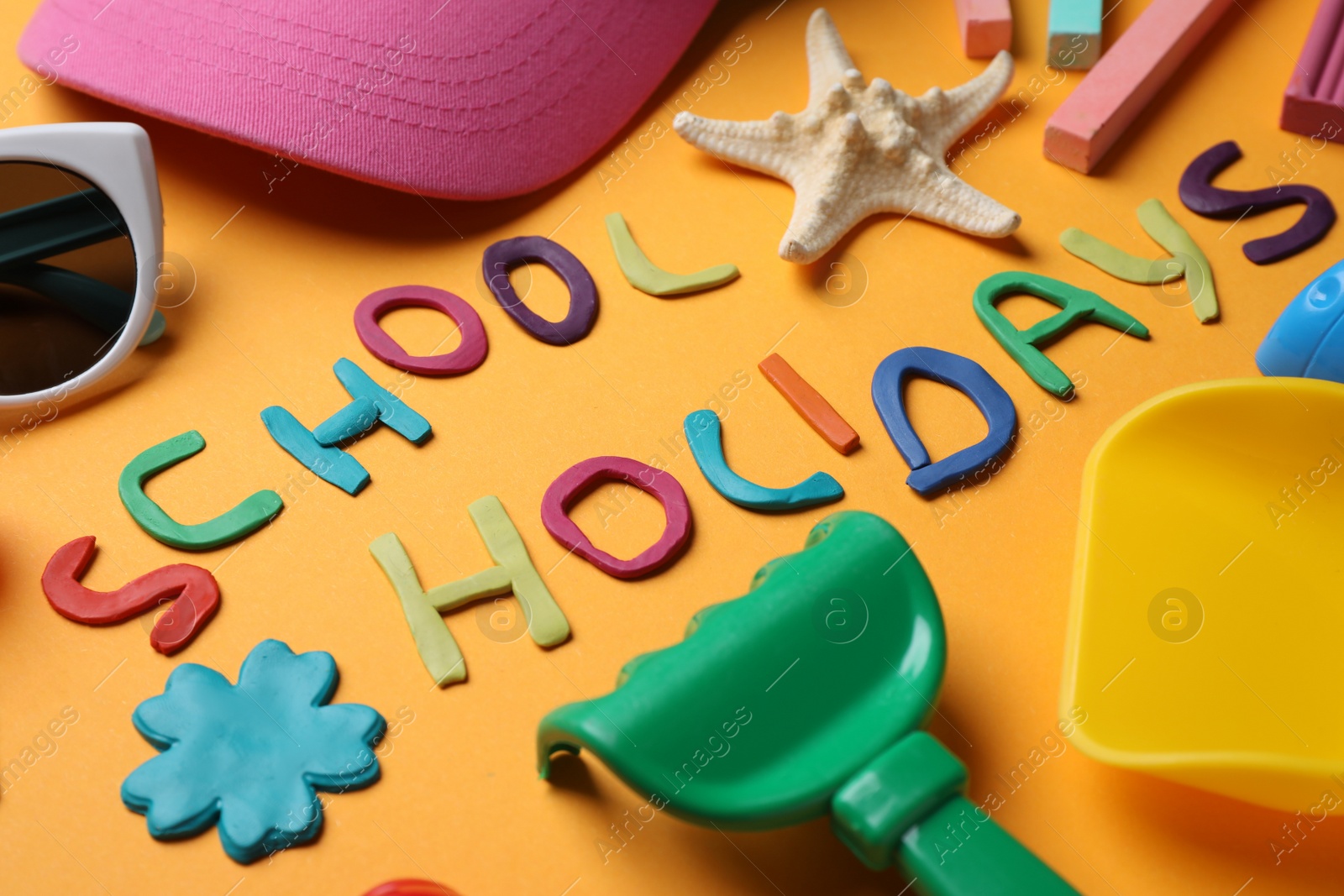 Photo of Composition with phrase School Holidays made of modeling clay on orange background