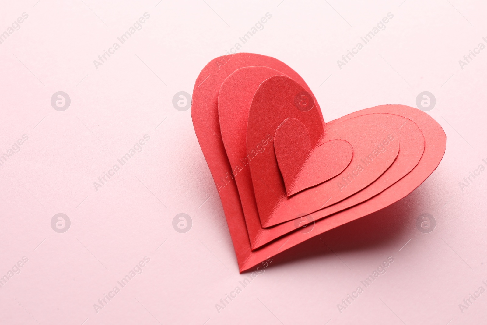 Photo of Red paper hearts on pink background. Space for text