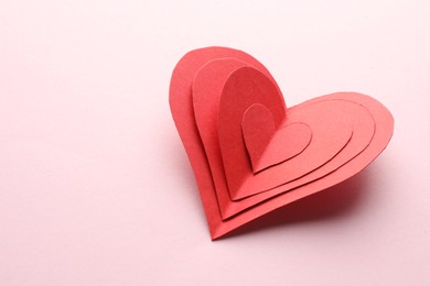 Red paper hearts on pink background. Space for text