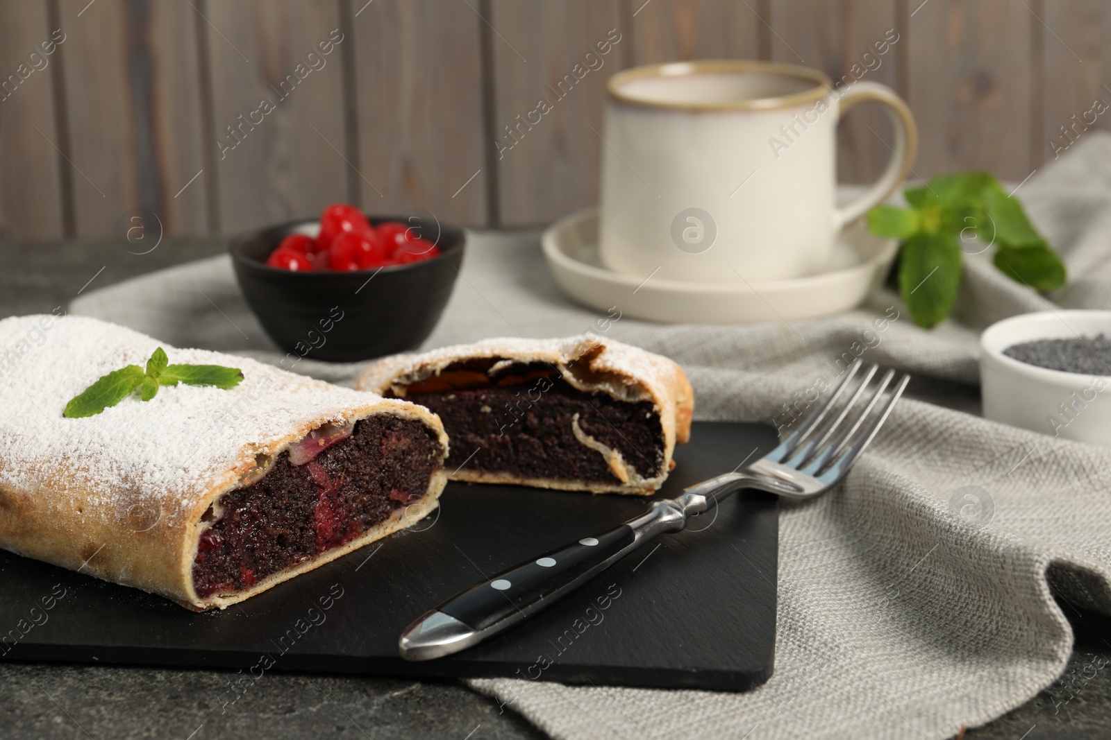 Photo of Delicious strudel with cherries and poppy seeds on grey table, closeup