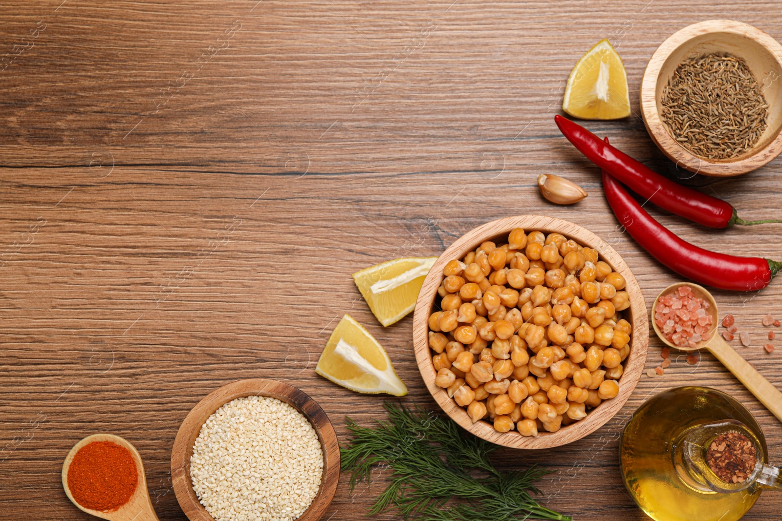 Photo of Delicious chickpeas and different products on wooden table, flat lay with space for text. Hummus ingredients