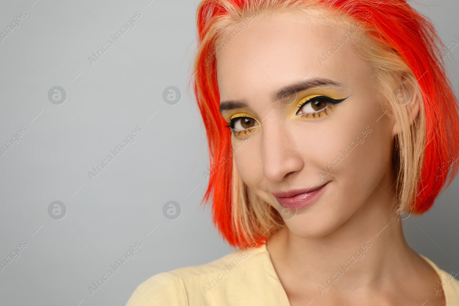 Photo of Beautiful young woman with bright dyed hair on light grey background, closeup. Space for text