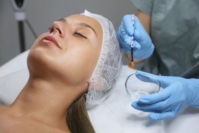 Photo of Cosmetologist applying chemical peel product on client's face in salon