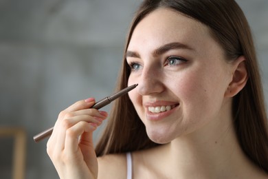 Photo of Smiling woman drawing freckles with pen indoors, closeup