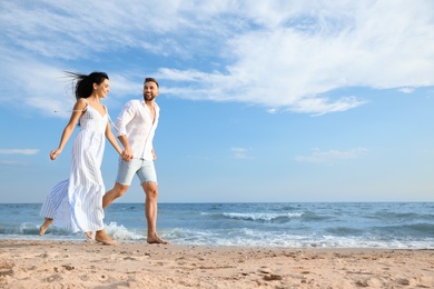 Happy young couple running together on beach