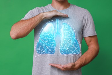 Man holding hands near chest with illustration of lungs on green background, closeup