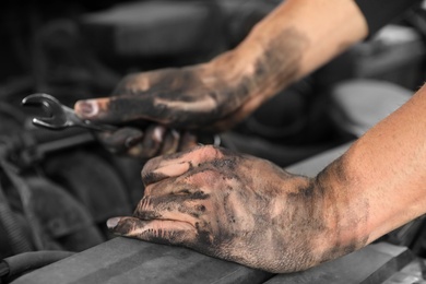 Photo of Dirty mechanic fixing car, closeup of hands