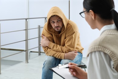 Photo of Psychotherapist working with drug addicted man indoors