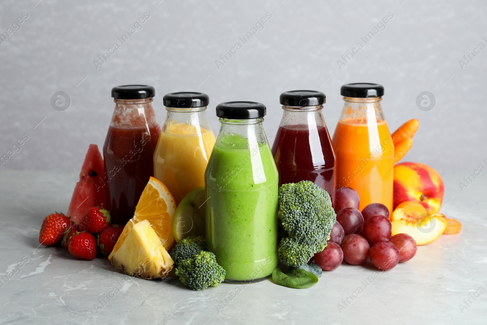 Photo of Bottles of delicious juices and fresh fruits on marble table