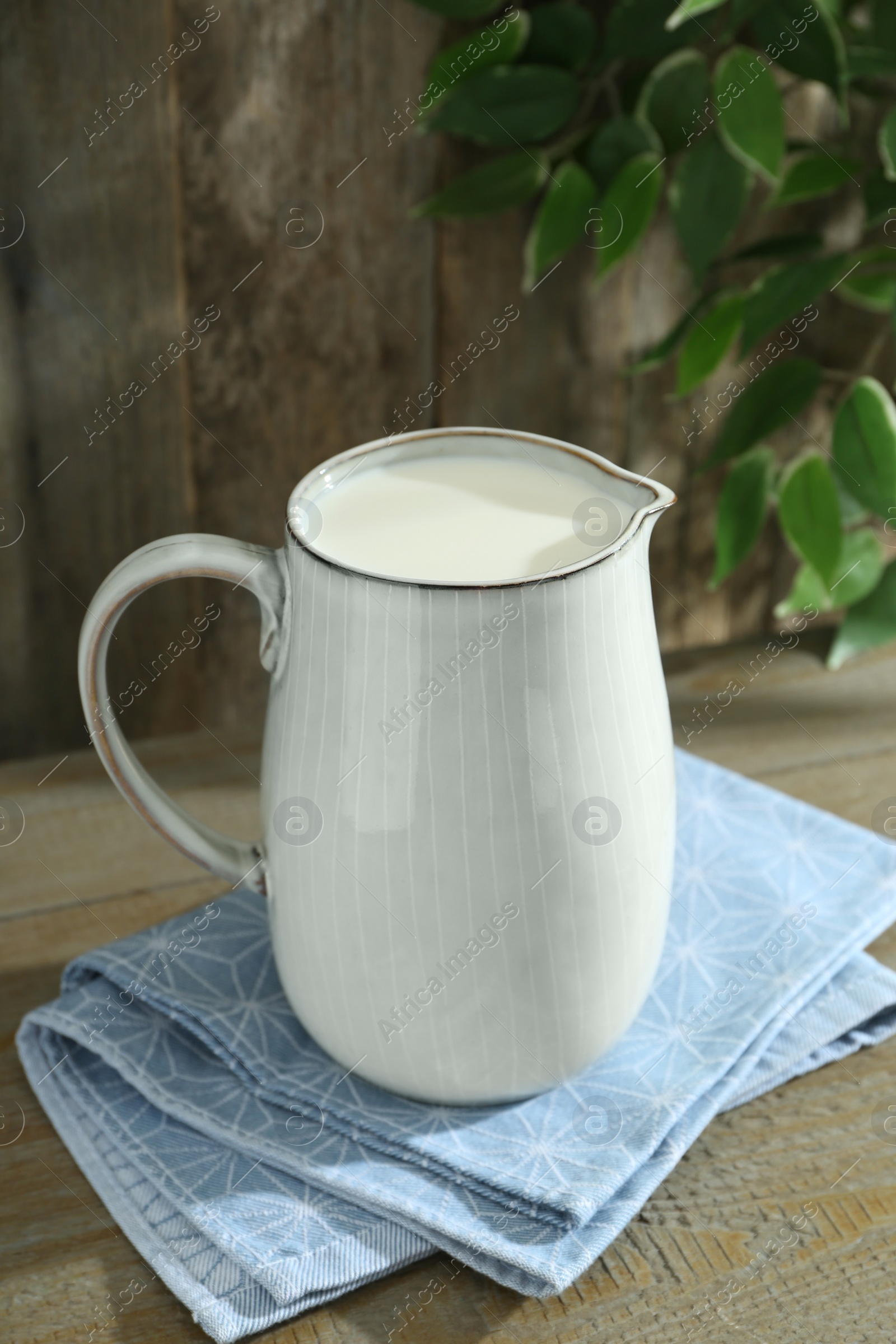 Photo of Jug of fresh milk on wooden table