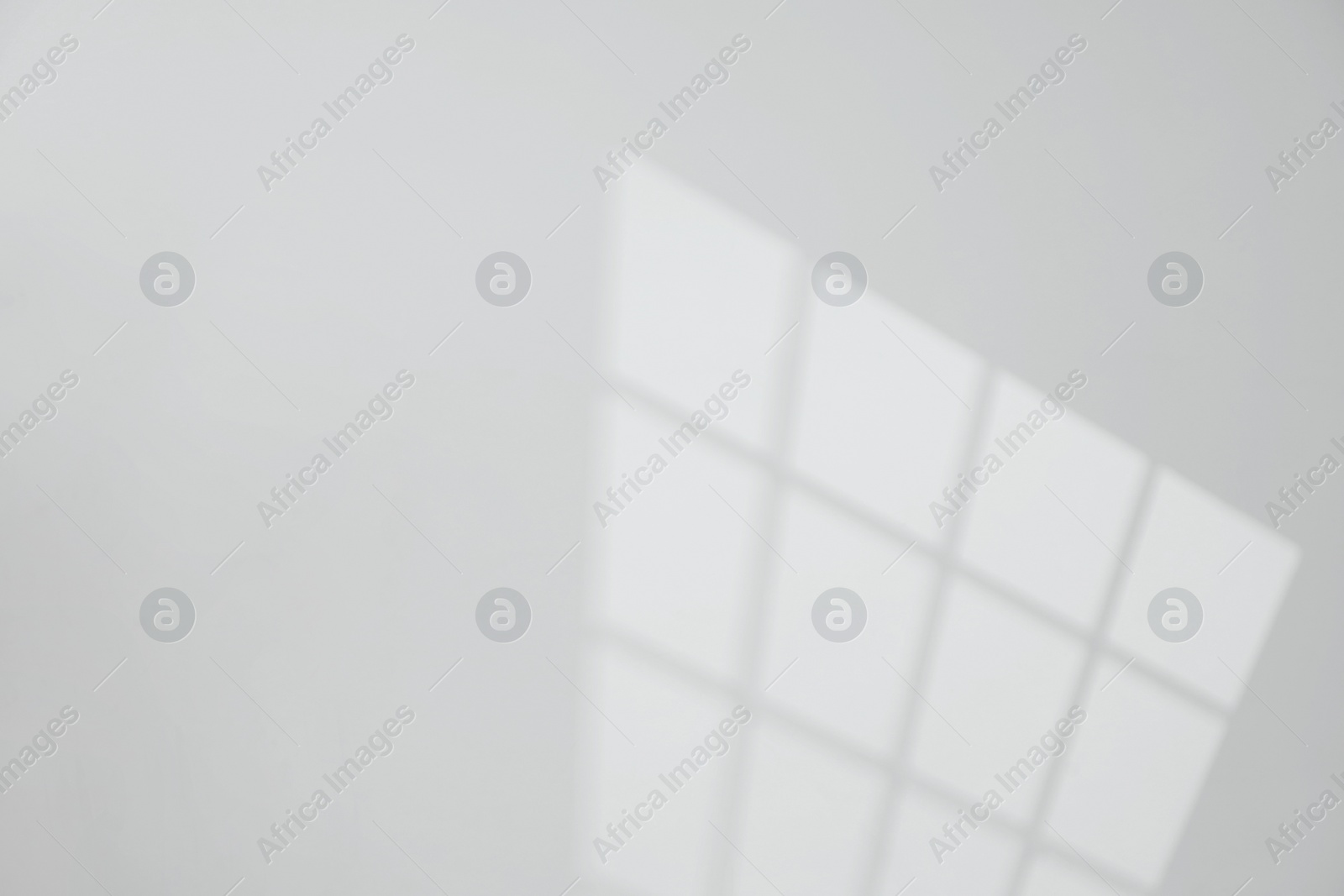 Photo of Light and shadow from window on white wall, space for text