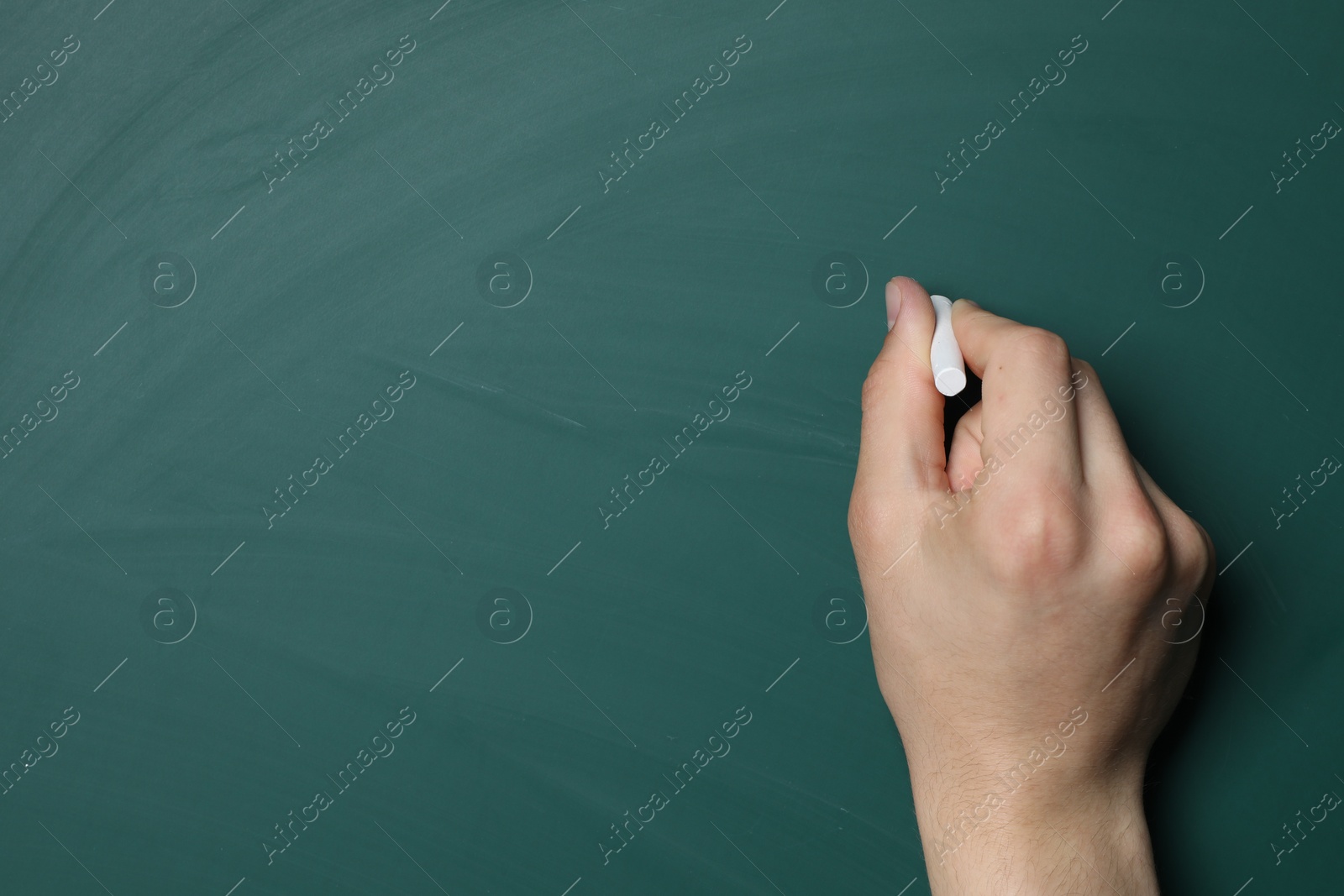 Photo of Teacher writing with chalk on green chalkboard, closeup. Space for text