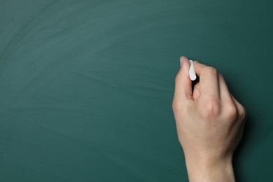 Teacher writing with chalk on green chalkboard, closeup. Space for text