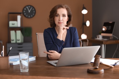 Photo of Female lawyer working with laptop at table in office