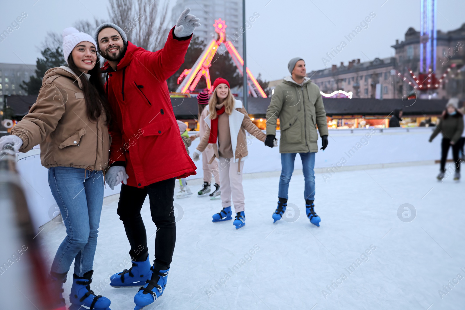 Image of Happy young couple near fence at outdoor ice rink