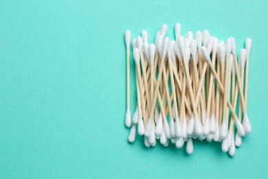 Photo of Heap of cotton buds on turquoise background, top view. Space for text