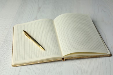 Photo of Open notebook and pen on white wooden table. Personal planning