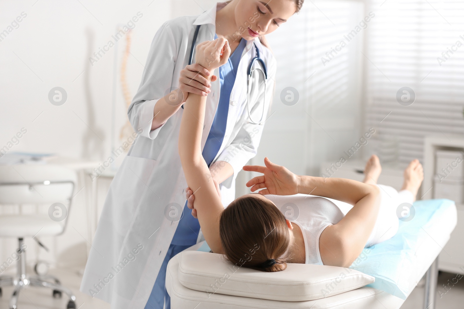 Photo of Female orthopedist examining patient's arm in clinic