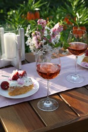 Vase with spring flowers, wine and cake on table served for romantic date in garden