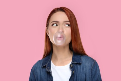 Photo of Portrait of beautiful woman blowing bubble gum on pink background