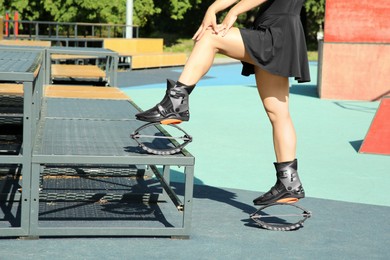 Photo of Woman with kangoo jumping boots in workout park, closeup