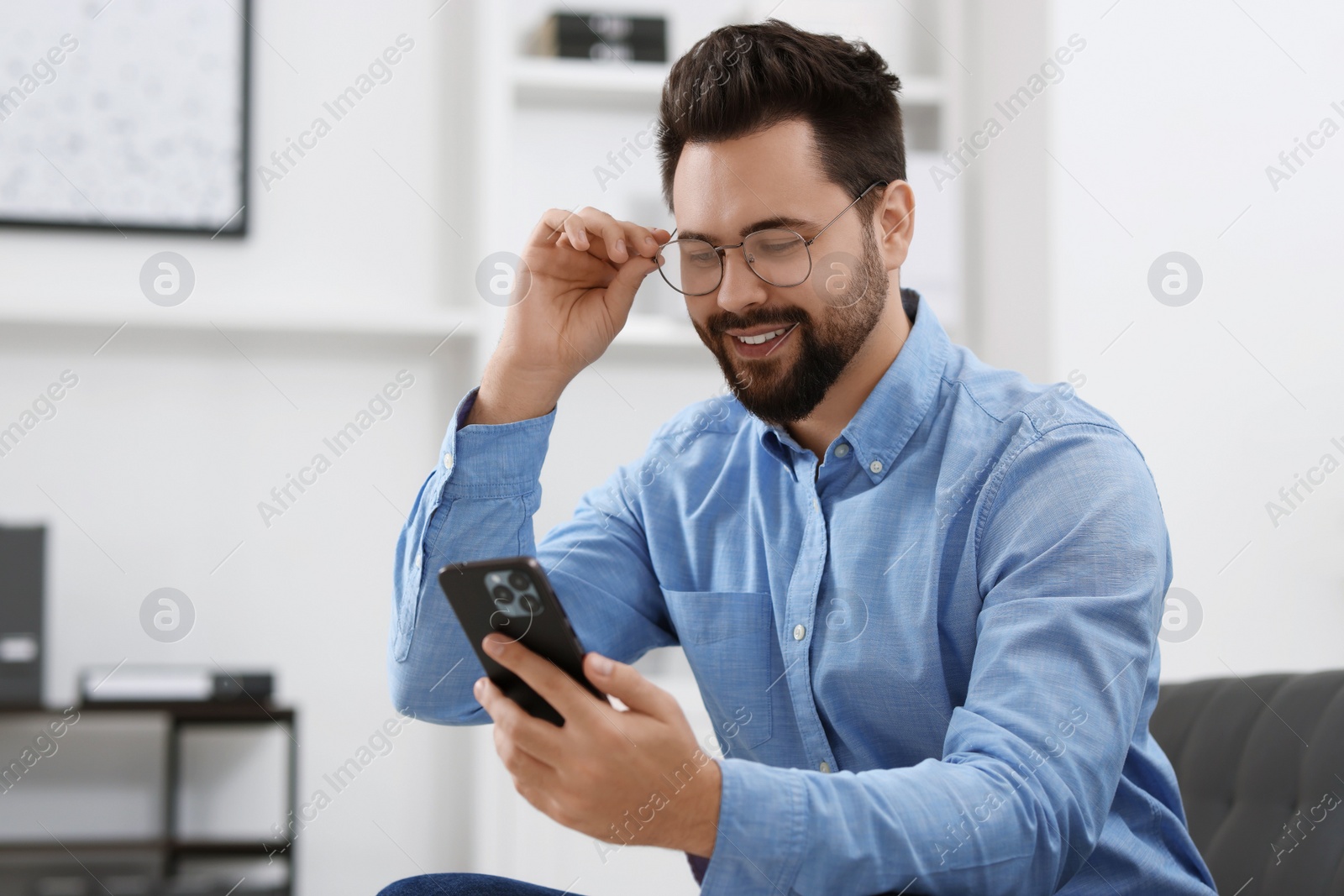 Photo of Handsome young man using smartphone in office