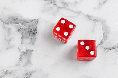 Two red game dices on white marble table, above view. Space for text