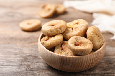 Photo of Tasty dried figs in bowl on wooden table