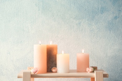 Candles with floral decor on table against color background