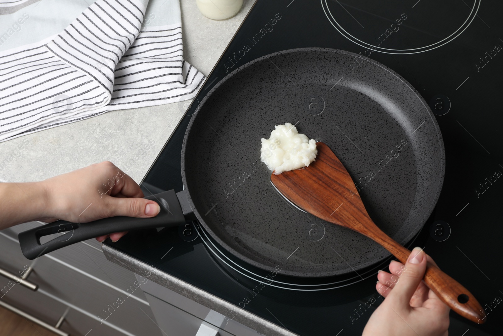 Photo of Woman cooking with coconut oil on induction stove, closeup