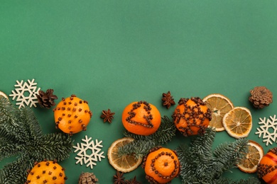 Flat lay composition with pomander balls made of fresh tangerines on green background. Space for text