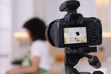 Photo of Food blogger recording video in kitchen, focus on camera