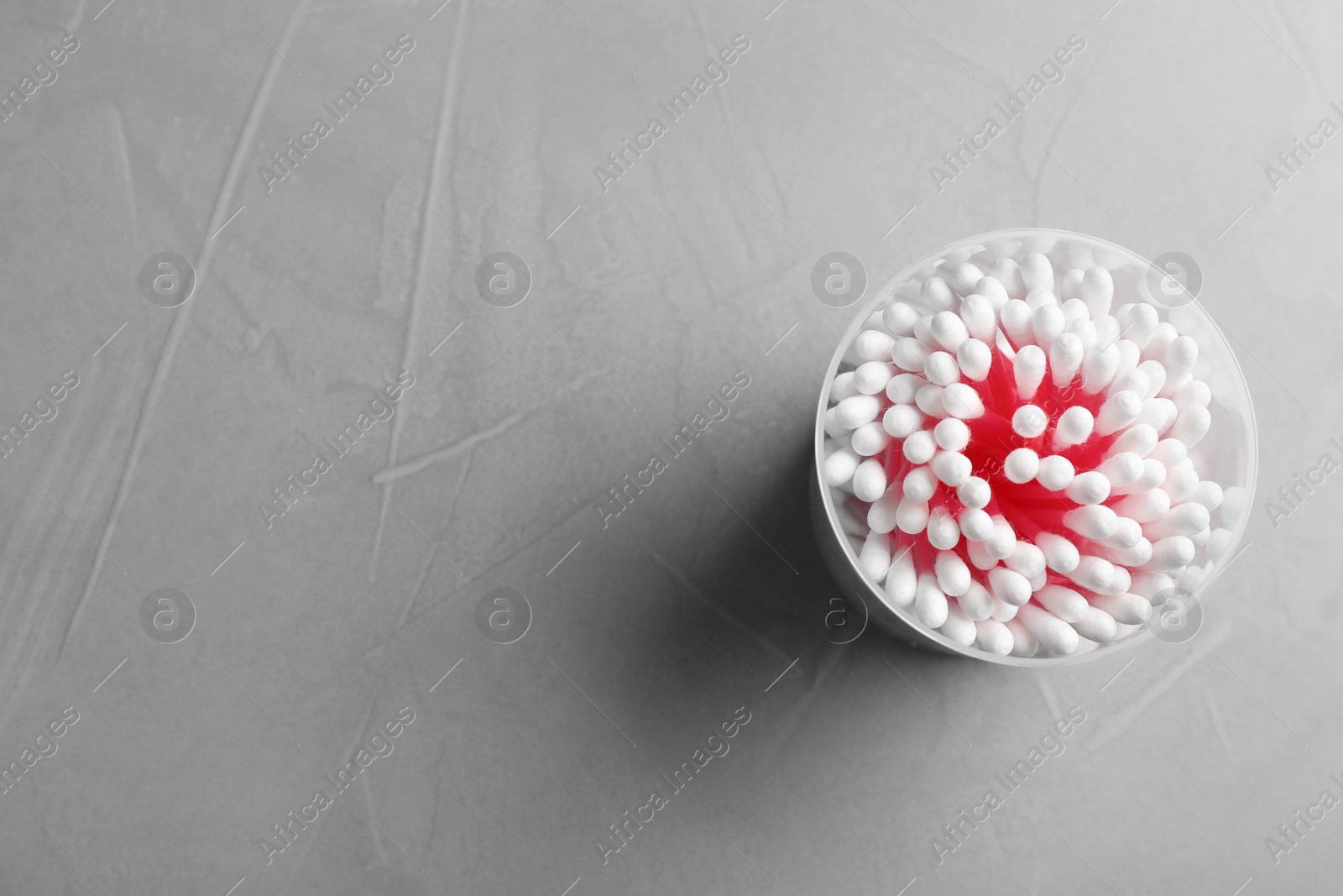 Photo of Plastic container with cotton swabs on grey background, top view. Space for text