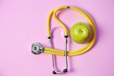 Photo of Flat lay composition with stethoscope and apple on color background