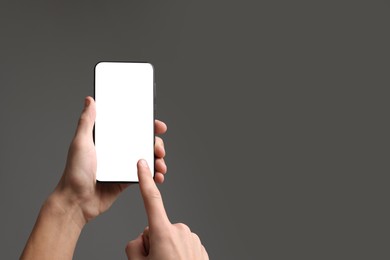 Photo of Man using smartphone with blank screen on grey background, closeup. Mockup for design